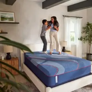 Family playing on a Sealy Brenham II Hybrid mattress in a bright, cozy bedroom setting, showcasing comfort and fun.