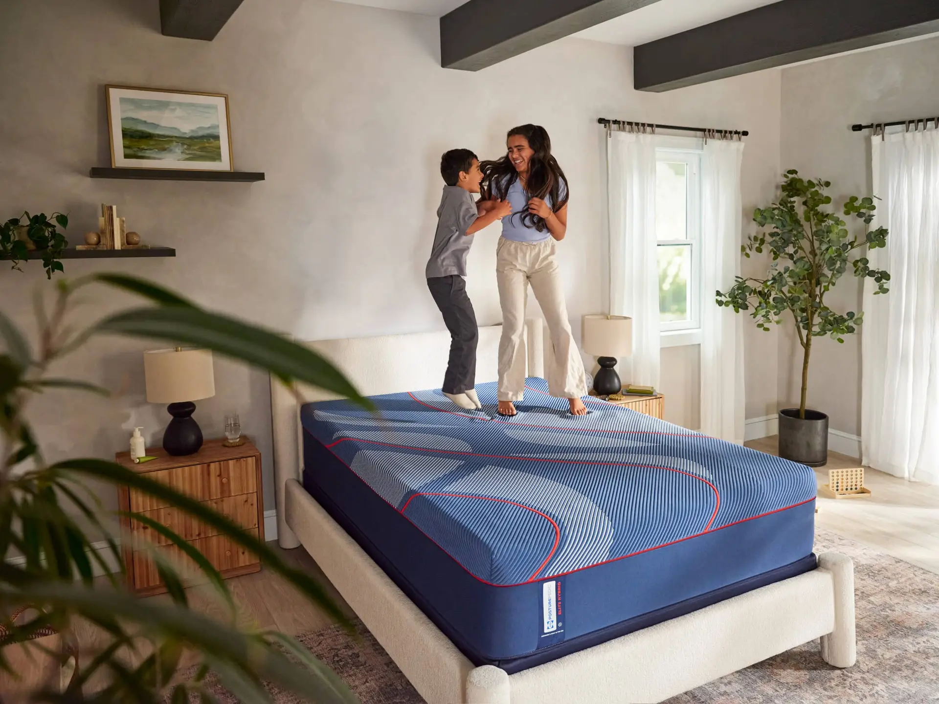 Family enjoying a playful moment on a Sealy Brenham II Hybrid mattress in a bright, modern bedroom setting, showcasing comfort and quality sleep solutions.