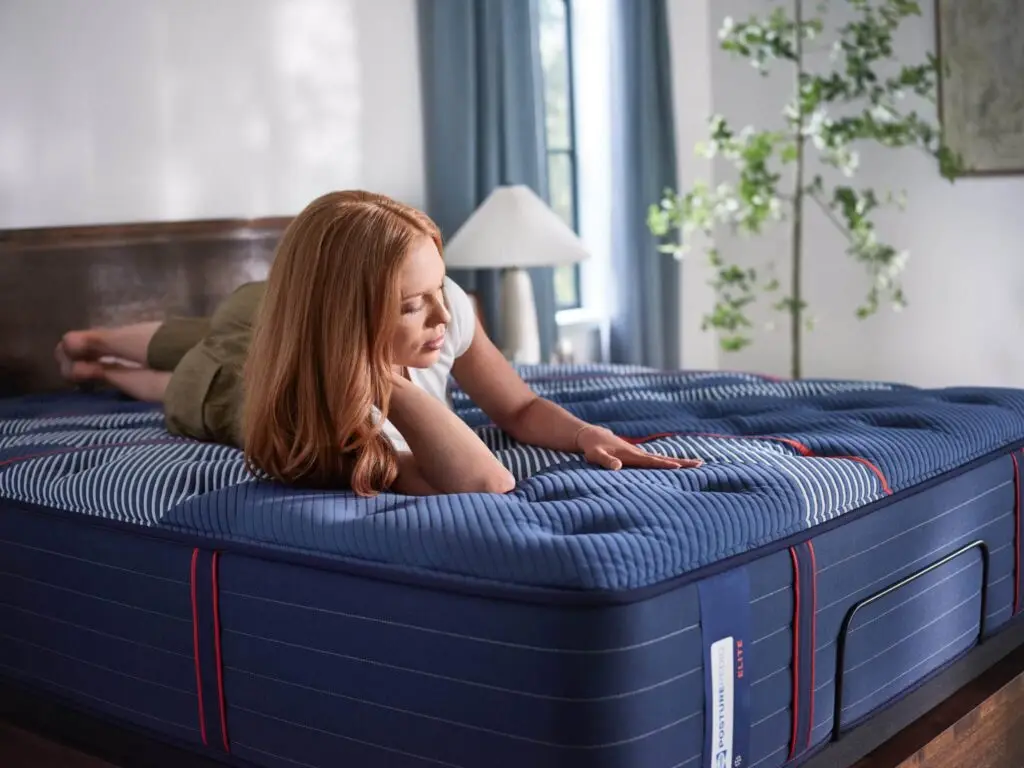 Woman lying on a blue-striped mattress, exploring its features in a bright bedroom, promoting Healthy ZZZ's cooling sleep solutions.