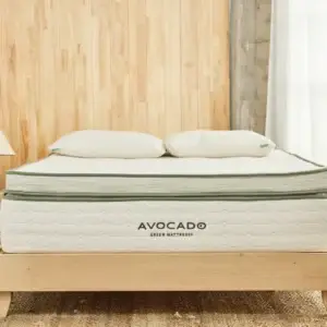 Avocado Green Mattress on wooden bed frame with two pillows, showcasing eco-friendly design and premium comfort for sleep enhancement.