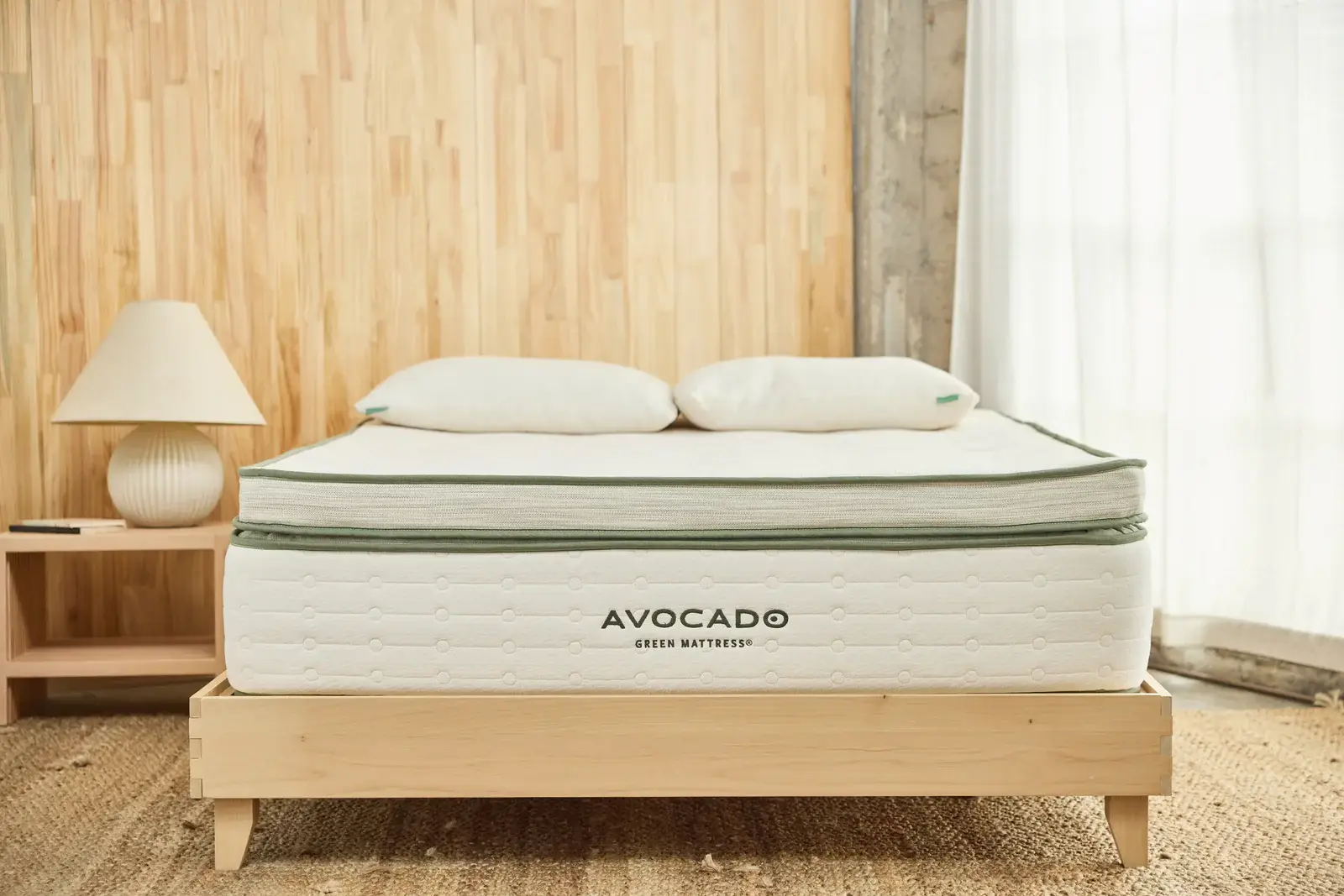 Avocado Green Box Top 1 Avocado Green Box Top mattress on a wooden bed frame, featuring organic materials, with two pillows and a minimalist decor setting.