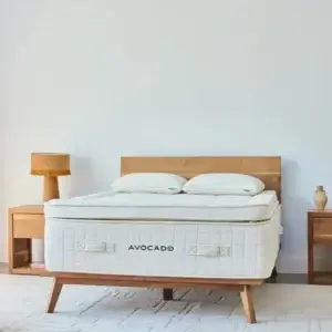 Avocado Luxury Organic Box Top mattress displayed in a modern bedroom setting with wooden furniture and soft lighting.