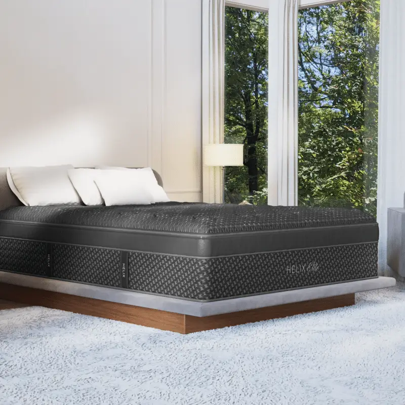 Helix Midnight Elite 2 Helix Midnight Elite mattress on a modern bed frame in a well-lit room with large windows, showcasing its luxurious design and comfort features.