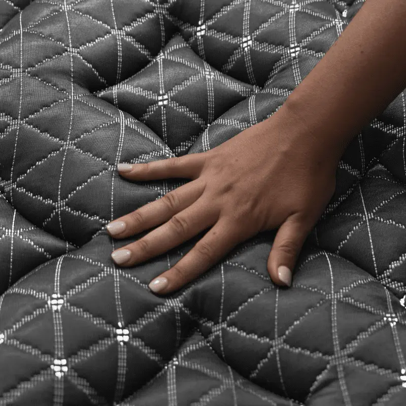 Helix Midnight Elite 3 Hand pressing down on the textured surface of the Helix Midnight Elite mattress, showcasing its luxurious quilted design and comfort features.