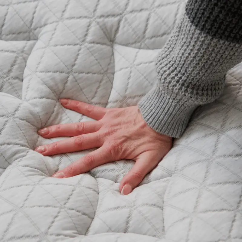 Helix Midnight Luxe 5 Hand pressing into the textured surface of the Helix Midnight Luxe mattress, showcasing its plush comfort and support features.