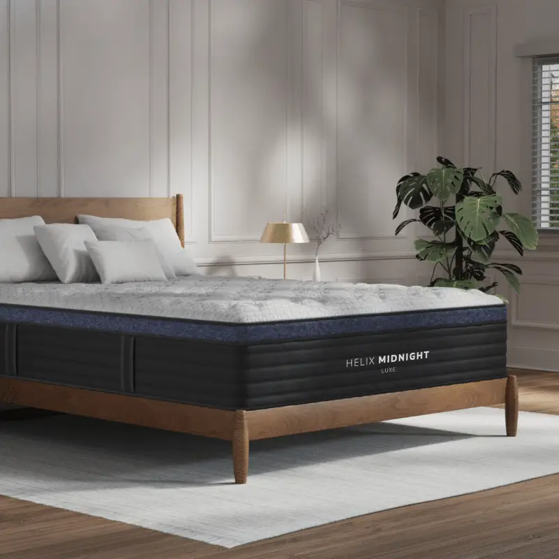 Helix Midnight Luxe 3 Helix Midnight Luxe mattress on a wooden bed frame in a stylish bedroom setting, featuring plush pillows and a decorative plant, emphasizing luxurious comfort for side sleepers.