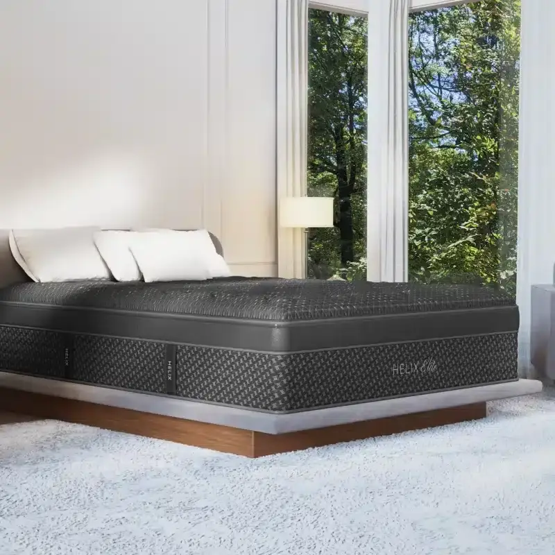 Helix Midnight Elite mattress displayed in a bright bedroom setting with large windows and decorative pillows, emphasizing comfort and wellness for better sleep solutions.