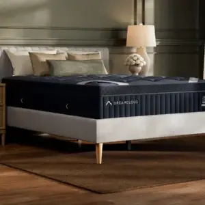 DreamCloud Luxe Hybrid mattress displayed in a stylish bedroom setting with a bedside lamp and decorative pillows, emphasizing luxury and comfort for quality sleep.