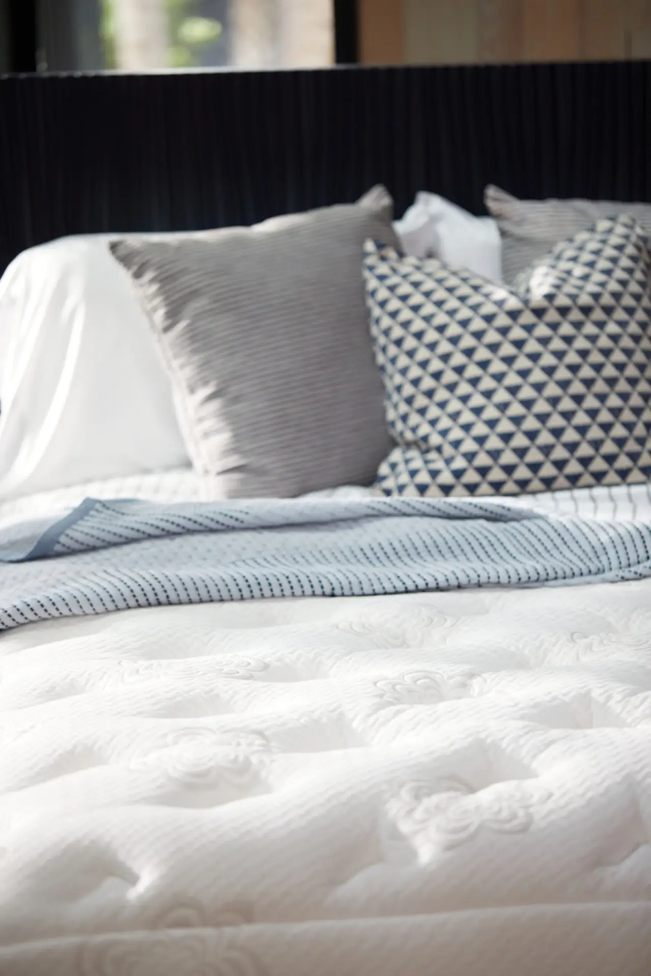Pranasleep Dharma Elite Hybrid 4 PranaSleep Dharma Elite Hybrid mattress with plush surface, decorative pillows, and a cozy blanket, emphasizing luxury and comfort.