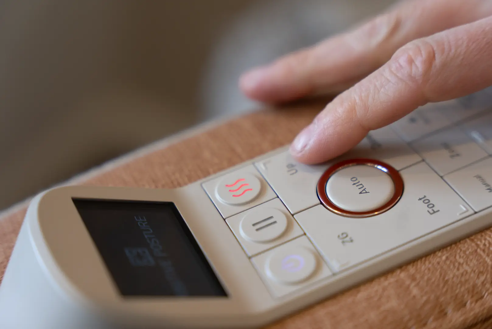 Positive Posture Solara 13 Close-up of a hand adjusting the control panel of the Positive Posture Solara massage chair, featuring buttons for heat, auto settings, and massage intensity.