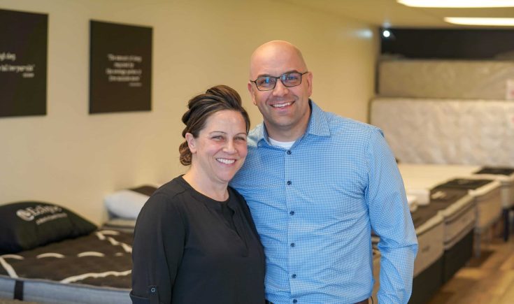 Smiling couple in a mattress store, showcasing expert mattress support and customer service at Healthy ZZZ's Sit & Sleep.