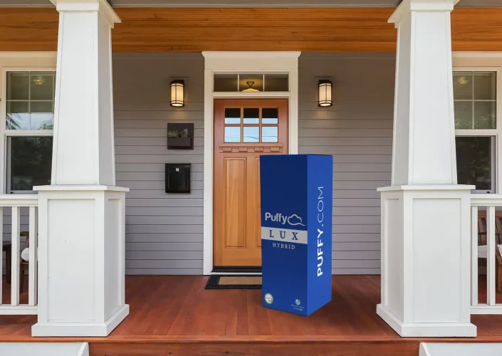 Puffy Lux Hybrid mattress box on a porch, showcasing delivery and comfort features, emphasizing quality sleep solutions.
