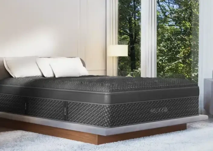 Helix Twilight Elite hybrid mattress on a modern bed frame, featuring a luxurious design with firm support, positioned near large windows overlooking greenery.